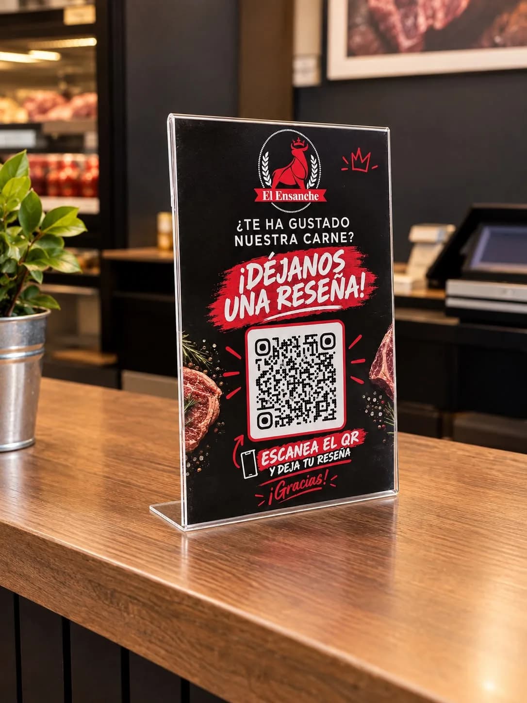 Soporte con flyer personalizado y código QR de El Gourmet del Ensanche sobre el mostrador, con el mensaje «¡Déjanos una reseña!»